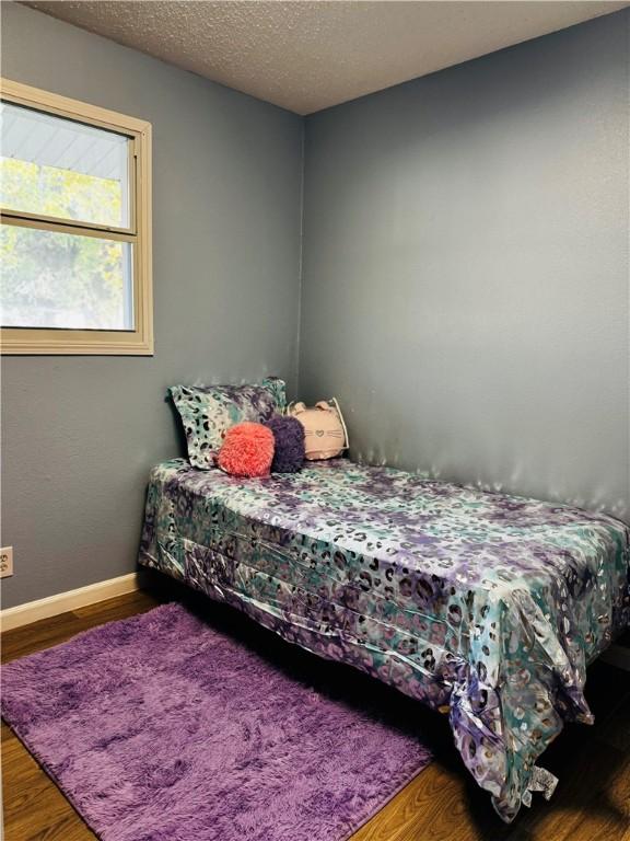 bedroom with a textured ceiling and hardwood / wood-style flooring