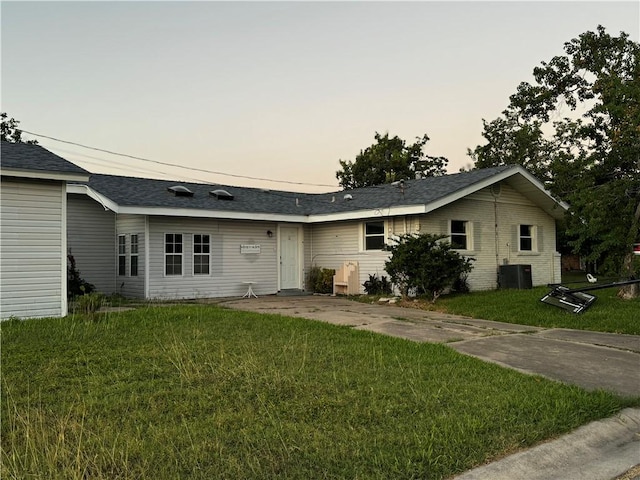 single story home with cooling unit and a yard