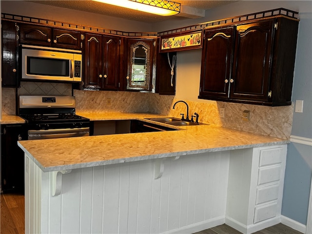 kitchen with sink, stainless steel appliances, dark hardwood / wood-style floors, backsplash, and kitchen peninsula