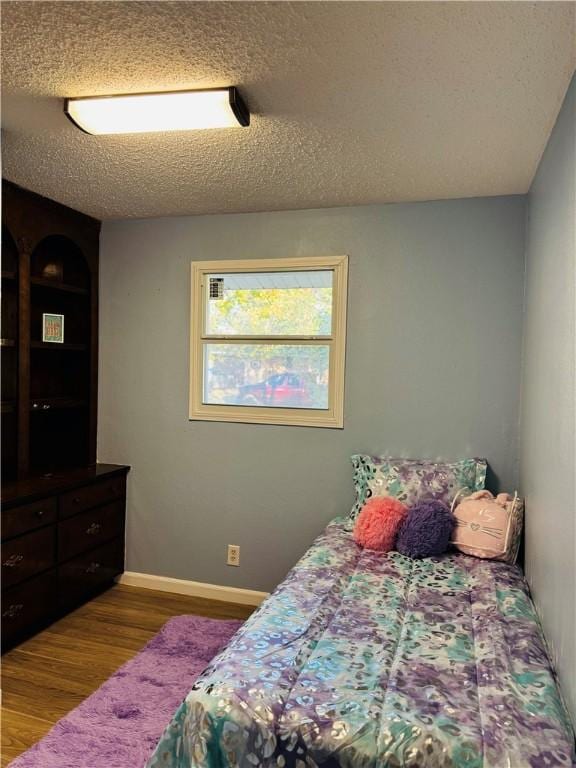 bedroom with hardwood / wood-style floors and a textured ceiling