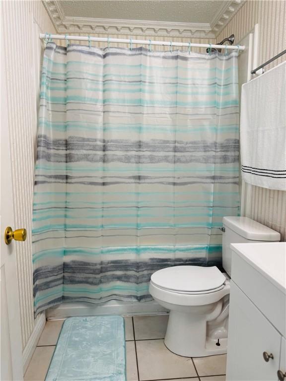 full bathroom with ornamental molding, vanity, shower / tub combo with curtain, tile patterned flooring, and toilet