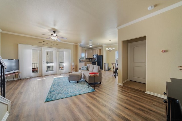 living room with hardwood / wood-style flooring, ceiling fan with notable chandelier, and crown molding