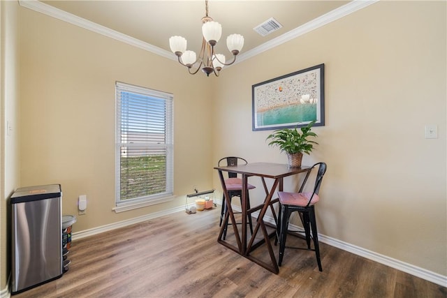 dining space featuring ornamental molding, hardwood / wood-style flooring, and a notable chandelier