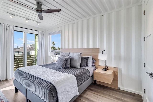 bedroom with track lighting, hardwood / wood-style floors, access to exterior, and ceiling fan