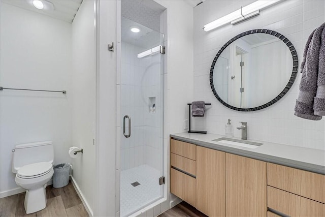 bathroom featuring tasteful backsplash, wood-type flooring, vanity, an enclosed shower, and toilet