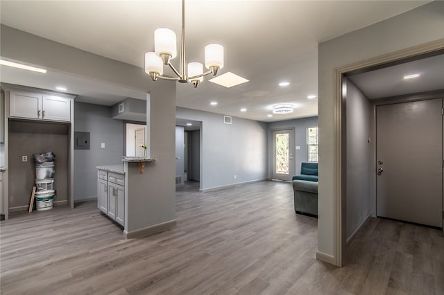 kitchen with hanging light fixtures, hardwood / wood-style flooring, a chandelier, and light stone counters