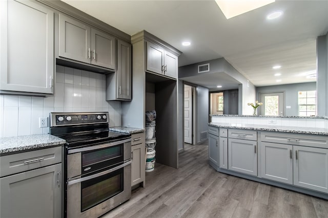 kitchen with gray cabinets, light hardwood / wood-style flooring, and stainless steel range with electric cooktop