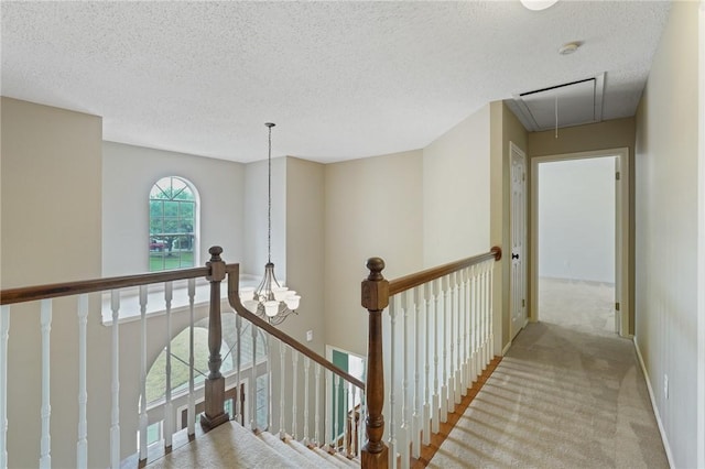 7617 Del Rio Dr, Corpus Christi, TX 78413 - hallway featuring attic access, an upstairs landing, carpet flooring, a textured ceiling, and a chandelier