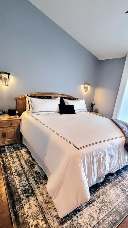 bedroom with lofted ceiling and wood finished floors