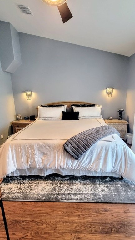 bedroom with ceiling fan, visible vents, and wood finished floors