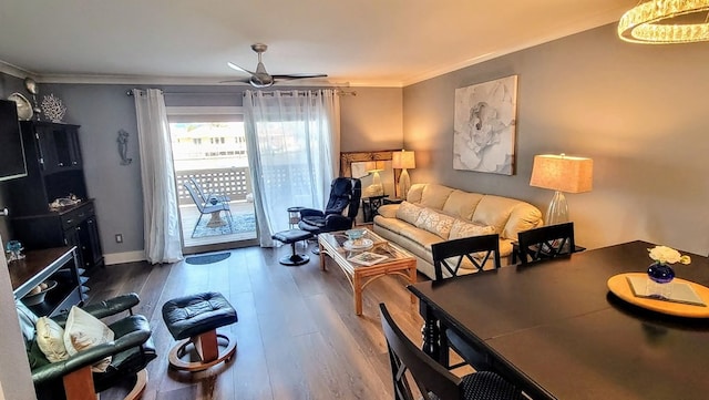 living room featuring a ceiling fan, crown molding, baseboards, and wood finished floors