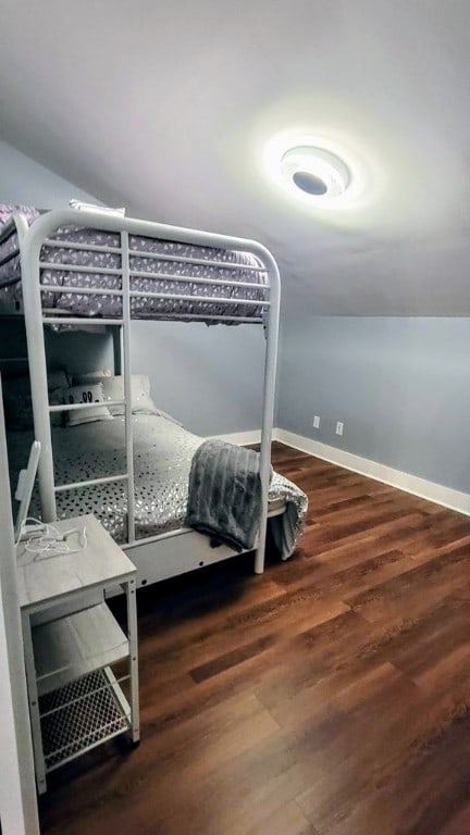 bedroom featuring lofted ceiling, baseboards, and wood finished floors