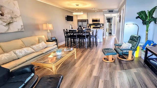 living room with ornamental molding, visible vents, baseboards, and wood finished floors