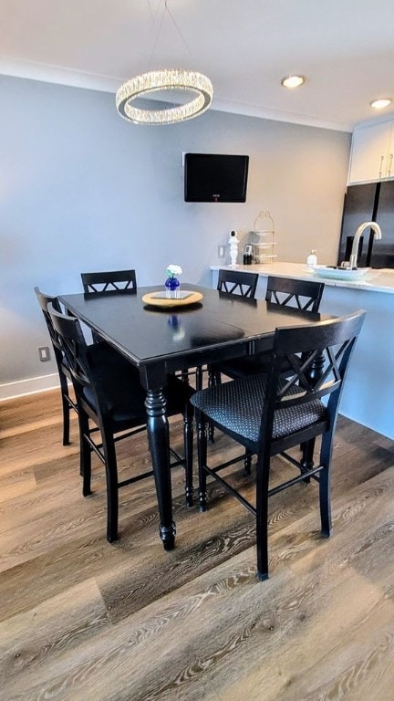 dining space featuring ornamental molding, recessed lighting, wood finished floors, and baseboards