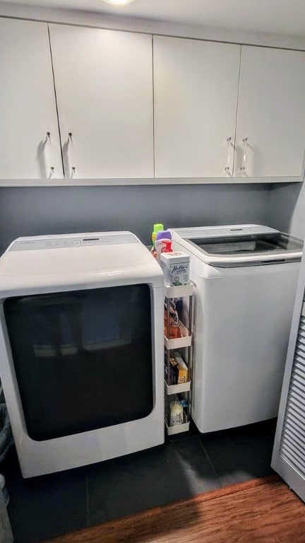 washroom with cabinet space, washer and dryer, and wood finished floors