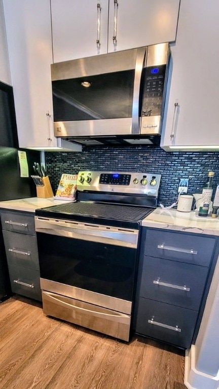 kitchen featuring appliances with stainless steel finishes, light countertops, decorative backsplash, and light wood finished floors