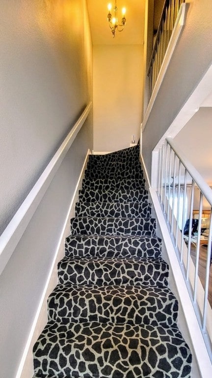 stairway featuring a chandelier, stone finish flooring, and baseboards