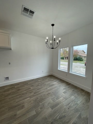 unfurnished dining area featuring dark hardwood / wood-style floors and an inviting chandelier