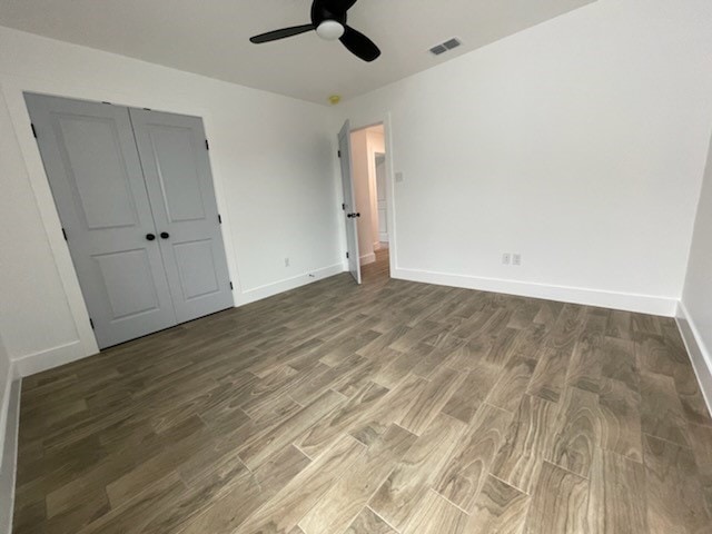 unfurnished bedroom featuring ceiling fan, dark hardwood / wood-style flooring, and a closet