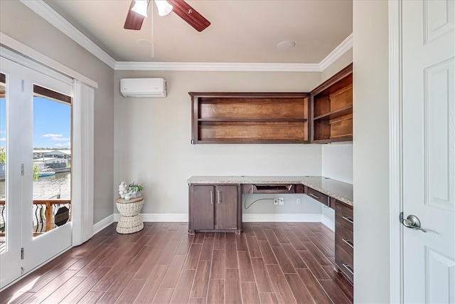 unfurnished office featuring built in desk, a wall mounted air conditioner, ornamental molding, ceiling fan, and dark wood-type flooring