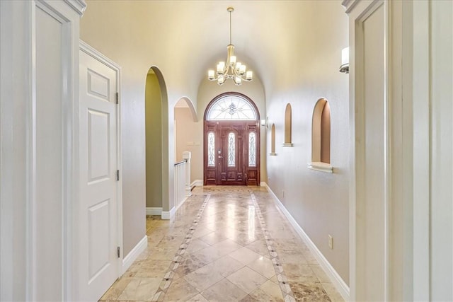 113 Bay Ct, Aransas Pass, TX 78336 - entrance foyer with inlaid floor details, arched walkways, a chandelier, baseboards, and a towering ceiling
