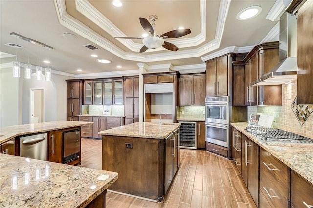 kitchen featuring stainless steel appliances, wine cooler, ornamental molding, light stone countertops, and a center island