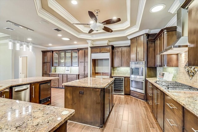 113 Bay Ct, Aransas Pass, TX 78336 - kitchen with beverage cooler, a center island, wall chimney range hood, ceiling fan, and ornamental molding