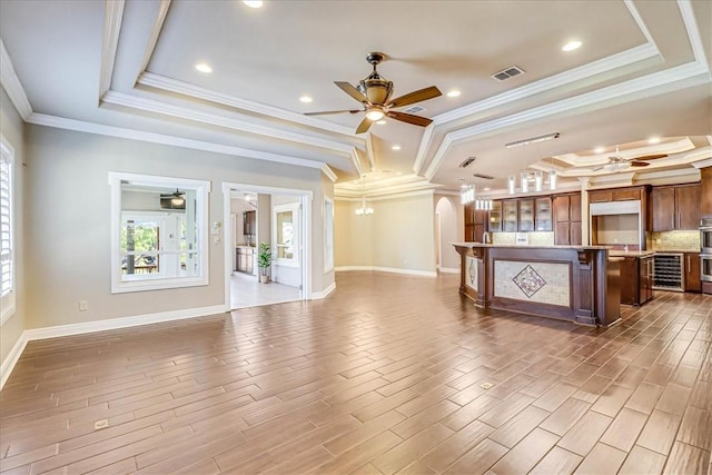 113 Bay Ct, Aransas Pass, TX 78336 - unfurnished living room with ceiling fan, a raised ceiling, beverage cooler, baseboards, and ornamental molding