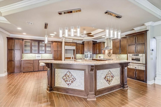 113 Bay Ct, Aransas Pass, TX 78336 - kitchen featuring oven, wall chimney range hood, a warming drawer, light wood-type flooring, and ornamental molding