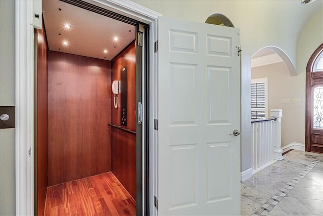 113 Bay Ct, Aransas Pass, TX 78336 - hall with elevator, arched walkways, baseboards, inlaid floor details, and light marble finish floors