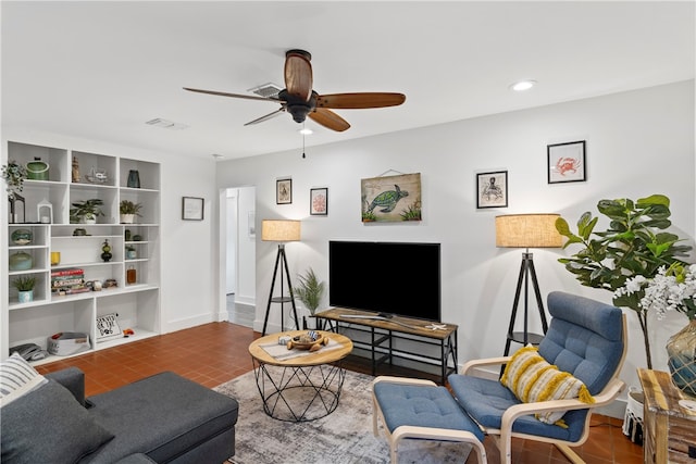 living room with ceiling fan and dark tile patterned floors