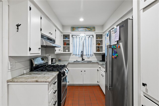 kitchen featuring dark tile patterned flooring, appliances with stainless steel finishes, sink, and white cabinets