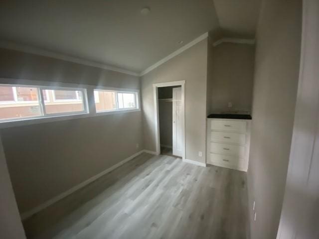 unfurnished bedroom with light hardwood / wood-style floors, vaulted ceiling, and ornamental molding