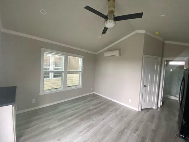 unfurnished living room with ceiling fan, a wall mounted air conditioner, crown molding, wood-type flooring, and vaulted ceiling