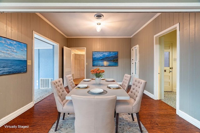 dining space with dark hardwood / wood-style flooring, wood walls, and crown molding