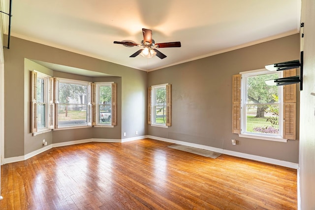 spare room featuring ornamental molding, light wood-type flooring, ceiling fan, and a healthy amount of sunlight