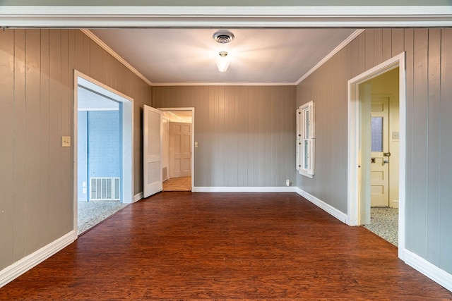 empty room featuring dark hardwood / wood-style flooring, wooden walls, and crown molding