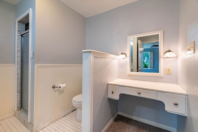 bathroom featuring toilet, wood walls, vanity, and a shower with door