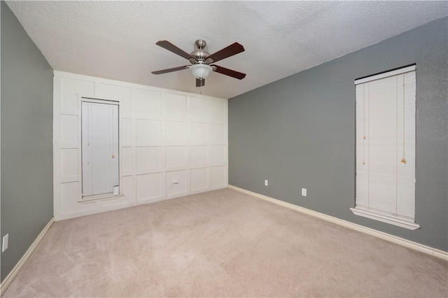 unfurnished bedroom featuring light carpet, a textured ceiling, and ceiling fan