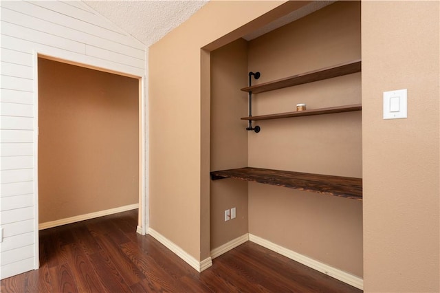 corridor featuring lofted ceiling, dark hardwood / wood-style floors, and a textured ceiling