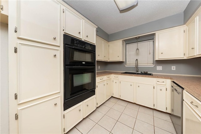 kitchen with double oven, sink, stainless steel dishwasher, light tile patterned floors, and a textured ceiling