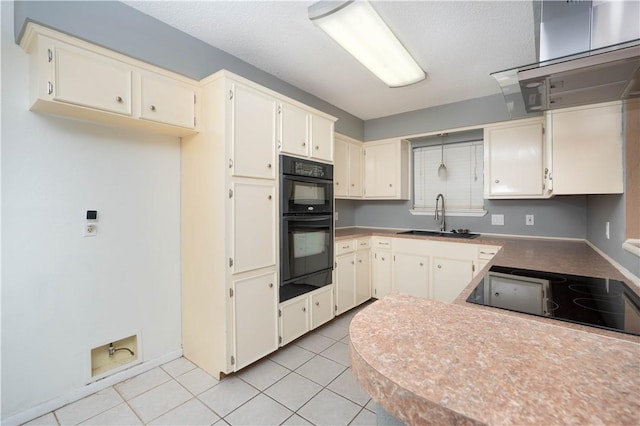 kitchen featuring light tile patterned flooring, sink, a textured ceiling, cream cabinets, and black appliances