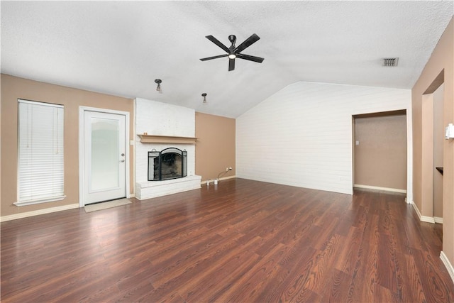 unfurnished living room with vaulted ceiling, dark wood-type flooring, a textured ceiling, and a fireplace