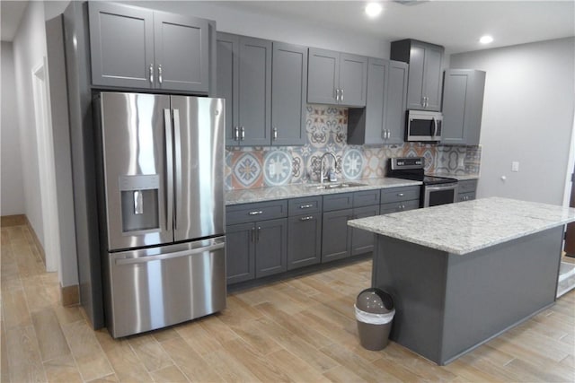 5334 Fm 1069th Rd N, Aransas Pass, TX 78336 - kitchen featuring stainless steel appliances, a sink, decorative backsplash, light stone counters, and a kitchen island