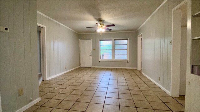 unfurnished room featuring a textured ceiling, light tile patterned floors, ceiling fan, and crown molding