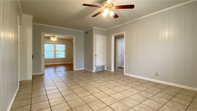 tiled spare room featuring ceiling fan and crown molding