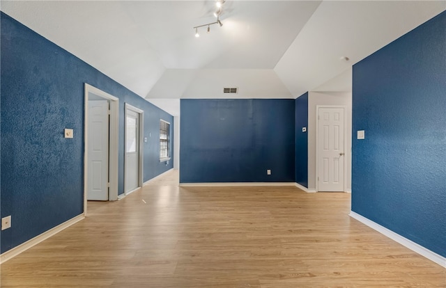 spare room with vaulted ceiling and light wood-type flooring