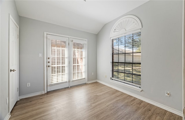 spare room featuring light hardwood / wood-style floors and vaulted ceiling