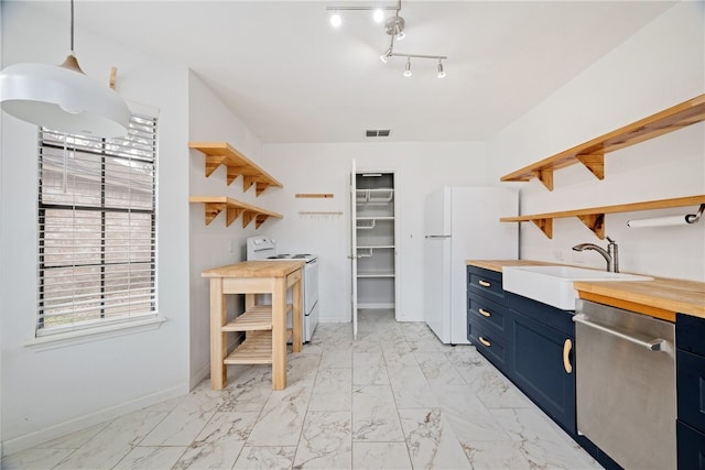 kitchen featuring pendant lighting, wood counters, blue cabinets, sink, and white appliances