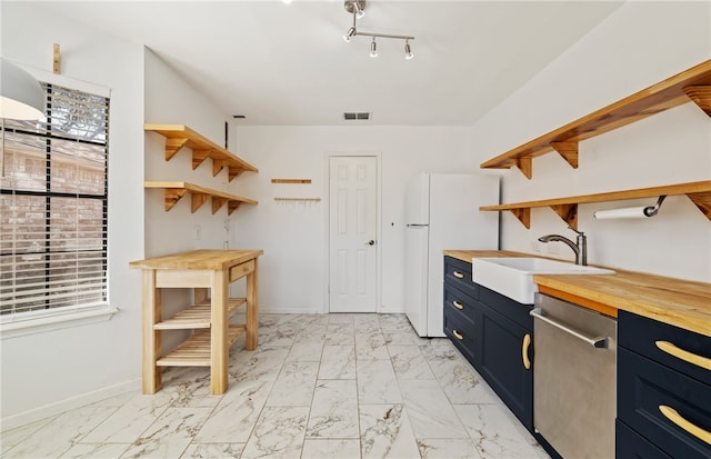 kitchen with blue cabinets, sink, wooden counters, stainless steel dishwasher, and white fridge